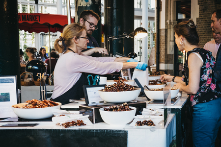 London, UK - September 17, 2018: People buying nuts at a market stall in Borough Market, one of the largest and oldest food markets in London, UK.のeditorial素材