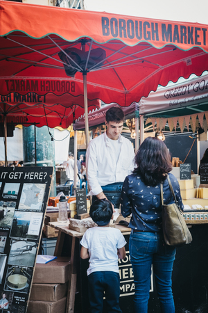 London, UK - September 17, 2018: Mother and son buying cheese at a stand in Borough Market, one of the largest and oldest food markets in London.のeditorial素材