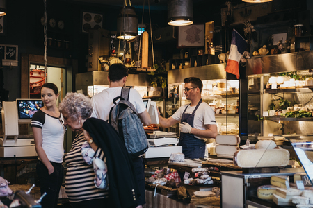 London, UK - September 17, 2018: Seller and customers inside charcuterie and cheese stand in Borough Market, one of the largest and oldest food markets in London.のeditorial素材