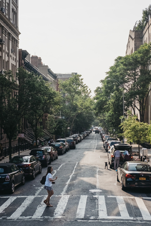 NEW YORK, USA - MAY 28, 2018: Woman crossing the road on a zebra crossing in New York, USA. New York...