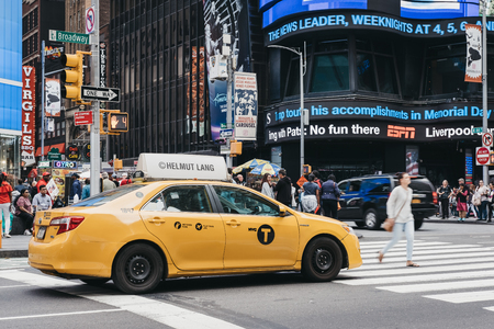New York, USA - May 28, 2018: Yellow taxi waiting on the traffic light in New York, pedestrians crossing in front of it. Yellow taxis are recognised worldwide as the icons of the city.のeditorial素材