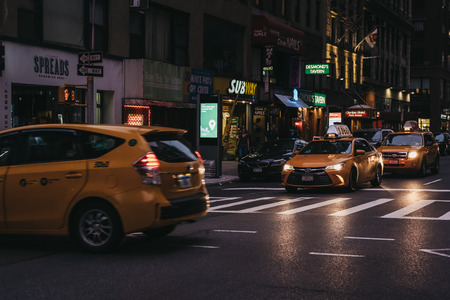 New York, USA - May 29, 2018: Numerous yellow taxis on the street in New York at night. Yellow taxis are recognised worldwide as the icons of the city.のeditorial素材