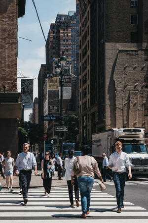 NEW YORK, USA - MAY 28, 2018: People crossing Fifth Avenue on a zebra crossing in New York, USA. New...
