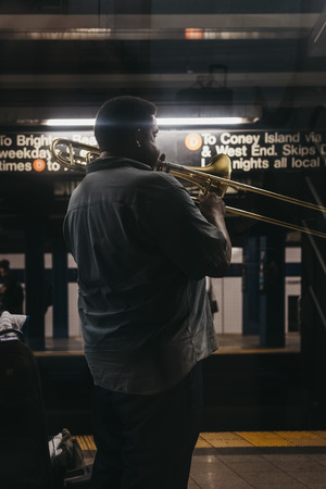 New York, USA - June 2, 2018: Man playing  musical instrument at subway station platform in New York. New York City Subway is one of the world's oldest public transit systems.のeditorial素材