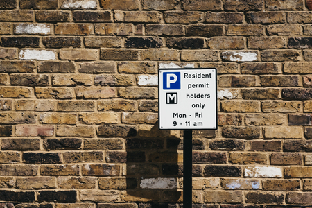 Close up of a sign with parking restrictions on a residential street in London, UK, against brick wall.の写真素材