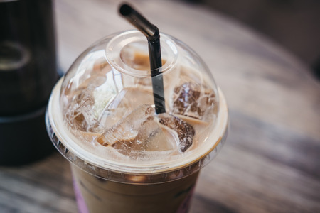 Close up of an iced coffee in a plastic cup with a straw on a table.の写真素材