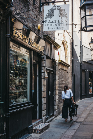 London, UK - August 1, 2018. Woman walking past Eastern Adornment shop on Brewers's lane, a street in Richmond, a suburban town in south-west London famous for large number of parks and open spacesのeditorial素材