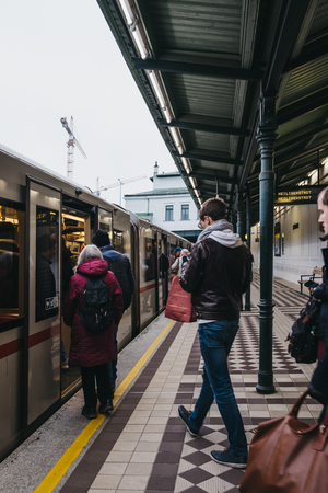 Vienna, Austria - November 25, 2018: People boarding the underground train at outdoor Schonbrunn station in Vienna. Vienna public transport, Wiener Linien, operates five underground lines.のeditorial素材