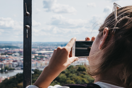 Prague, Czech Republic - August 26, 2018: Woman taking photos on smartphone from Petrin Tower,...