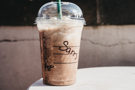 Prague, Czech Republic - August 26, 2018: Starbucks iced coffee with cream in transparent plastic cup with name Sam on an outdoor table in summer. Starbucks is a famous American coffeehouse chain.のeditorial素材