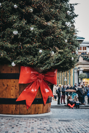 London, UK - January 5, 2019: People walking by the Giant Christmas tree in a pot with a gift tag in front of Covent Garden Market, one of the most popular tourist sites in London, UK.のeditorial素材