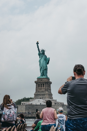 New York, USA - June 02, 2018: Tourists taking photos of Statue of Liberty from a tour boat on Hudson river, New York, USA. New York is one of the most visited cities in the world.のeditorial素材
