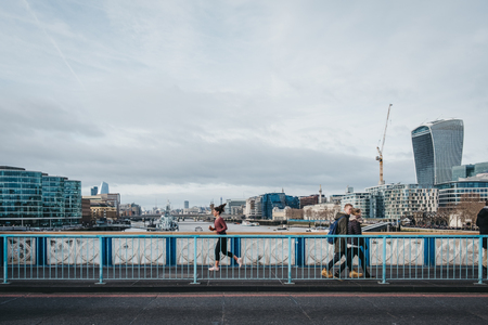 London, UK - January 13, 2019: Running woman and pedestrians on London Bridge, London, UK, River Thames and the city on the background. Running is a popular way to stay fit in UK.のeditorial素材