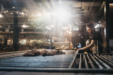 London, UK - January 13, 2019: Man cooking at a stand in Mercato Metropolitano, sustainable community market in London focused on revitalising the area and protecting environment.のeditorial素材