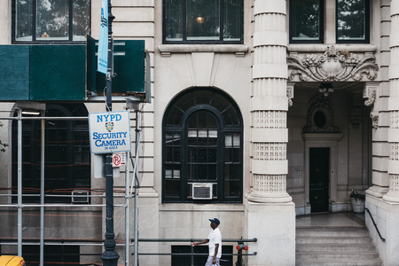 New York - June 1, 2018: African American man walking by NYPD Cameras sign in Manhattan, New York....