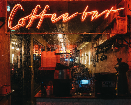 London, UK - January 26, 2019: Illuminated window and neon sign on a Coffee Bar in Canary Wharf on a rainy evening. Canary Wharf is a busy financial area of London that often host events.のeditorial素材