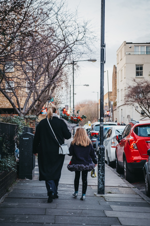 London, UK - February 03, 2019: People walking on a street with flowers purchased at the Columbia Road Flower Market, a street market in East London that is open every Sunday.のeditorial素材