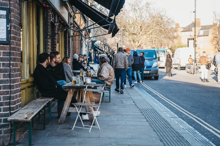 London, UK - February 03, 2019: People sitting at an outdoor table of a cafe on Broadway Market, a shopping street in the heart of Hackney, East London, UK.のeditorial素材