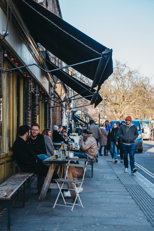 London, UK - February 03, 2019: People sitting at an outdoor table of a cafe on Broadway Market, a shopping street in the heart of Hackney, East London, UK.のeditorial素材