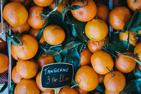 Pile of fresh satsumas with stems and leaves on sale at a street market.の写真素材