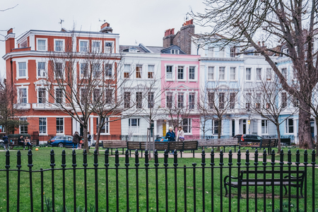 London, UK - February 16, 2019: People in Chalcot Square Gardens, colourful terraced houses of Primrose Hill on the background. Primrose Hill is one of the most expensive residential areas in London.のeditorial素材