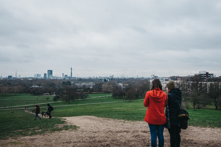 London, UK - February 16, 2019: People on Primrose Hill, 65 m hill on the northern side of Regent's Park, London, that has also given name to the surrounding district. City on the back.のeditorial素材