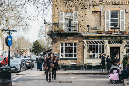 London, UK - March 2, 2019: People walking past King William pub in Hampstead, an affluent area favoured by academics, artists and media figures.のeditorial素材