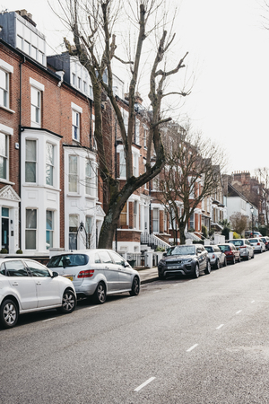 London, UK - March 2, 2019: Row of typical British terraced houses in Hampstead, an affluent residential area of London favoured by artists and media figures, cars parked outside.のeditorial素材