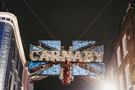 London, UK - March 6, 2019: Large Carnaby and Union Jack 3D shimmer sign over the junction between Carnaby Street and Ganton Street, at night. It is made of 30,000 red, white and blue shimmer discs.のeditorial素材