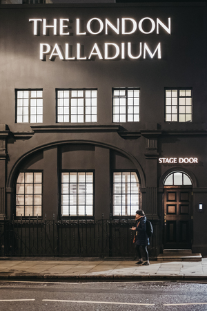 London, UK - March 6, 2019: Woman walking past the stage entrance to London Palladium Theatre,  one of most famous theatres in London and the UK, especially for musical variety shows.のeditorial素材
