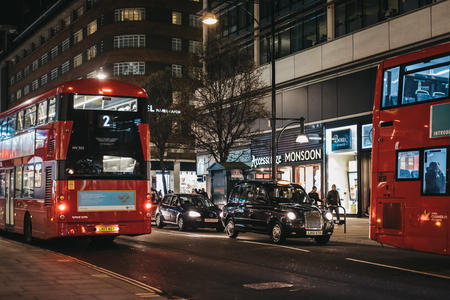 London, UK - March 9, 2019: Red double decker buses and taxis on Oxford Street, London, in the evening. Oxford street is one of the most famous shopping streets in London.のeditorial素材