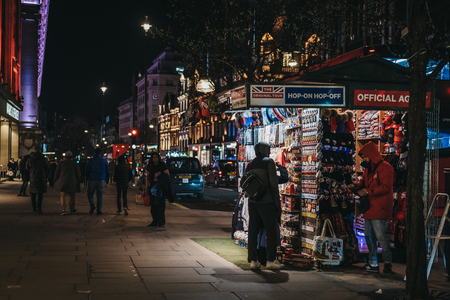 London, UK - March 9, 2019: People looking at souvenirs at a tourist stand on Oxford Street, London, in the evening. London is one of the most visited cities in the world.のeditorial素材
