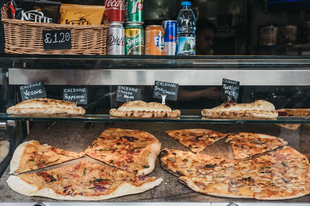 London, UK - March 23,2019: Pizza and calzone on sale at a food stall inside Camden Market, London. Started with 16 stalls in 1974, Camden Market is one of the busiest retail destinations in London.のeditorial素材