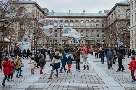 Paris, France - January 27, 2018: Kids chasing giant soap bubbles on a street in Paris, France, one of the most visited cities in the world.のeditorial素材