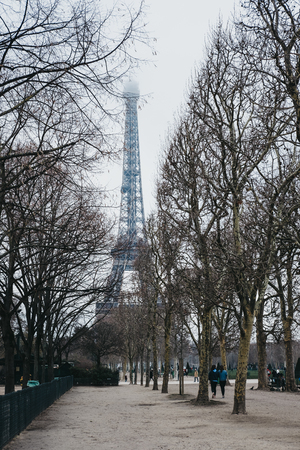 Paris, France - January 27, 2018: People walking on Champ de Mars in Paris, Eiffel Tower on the...