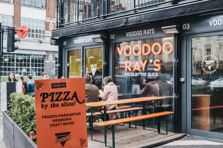 London, UK - April 6, 2019: People eating pizza outside Voodoo Rays cafe at BOXPARK Shoreditch, shipping container pop-up mall for fashion and lifestyle stores and cafes.のeditorial素材