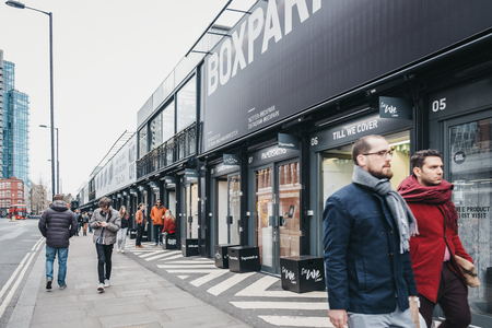 London, UK - April 6, 2019: People walking past the shops at BOXPARK Shoreditch, London, shipping...