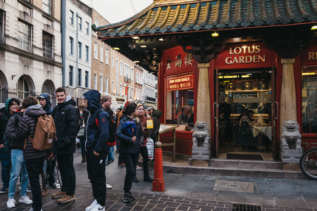 London, UK - April 13, 2019: People walking past restaurants in Chinatown, London. Chinatown is home to a large East Asian community and is famous for its eateries and events.のeditorial素材