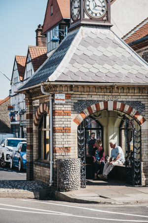 Sheringham, UK - April 21, 2019: People waiting for a bus inside a retro bus stop hut on a high street in Sheringham, an English seaside town within the county of Norfolk, UK.のeditorial素材