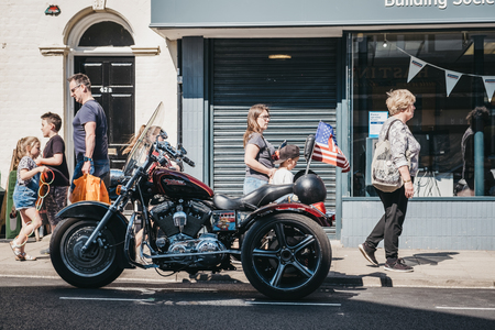 Sheringham, UK - April 21, 2019: People walking past Harley Davidson motorcycle parked on a side of the road in Sheringham, an English seaside town within the county of Norfolk, UK.のeditorial素材