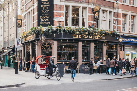 London, UK - April 13, 2019: Rickshaw on a street in front of The Cambridge, a traditional pub of unique character next to the Palace Theatre on Charing Cross Road, West End, London.のeditorial素材