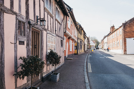 Lavenham, UK - April 19, 2019: Row of half-timbered pastel pink medieval cottages in Lavenham, a...