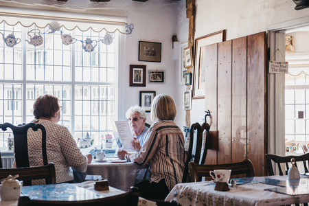 Lavenham, UK - April 16, 2019: Senior ladies at a table inside Blue Vintage Tea Rooms, a famous cafe in Grade II listed 15th Century cottage in Lavenham, serving traditional afternoon teas and cakes.のeditorial素材