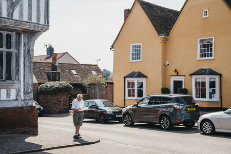 Lavenham, UK - April 19, 2019: Man standing and reading a map in front of colourful cottages in Lavenham, a village in Suffolk, England, famous for its Guildhall, Little Hall and its architecture.のeditorial素材