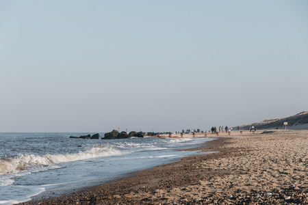 View of Horsey Gap beach, Norfolk, UK, on a sunny spring day, selective focus, unidentifiable people on horizon.の写真素材