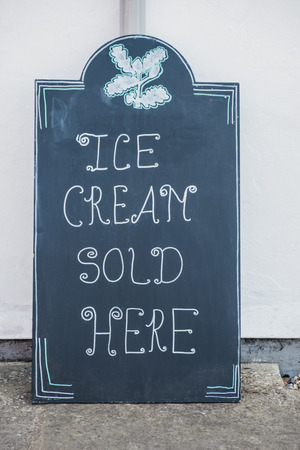 Close up of a black chalkboard "Ice-cream sold here" signの写真素材