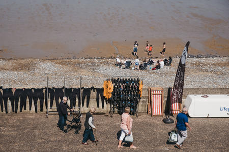 Cromer, UK - April 20, 2019: View from above of people walking past the wet suits drying in the sun at Surf School in Cromer, a seaside town in Norfolk and a popular family holiday destination in UK.のeditorial素材