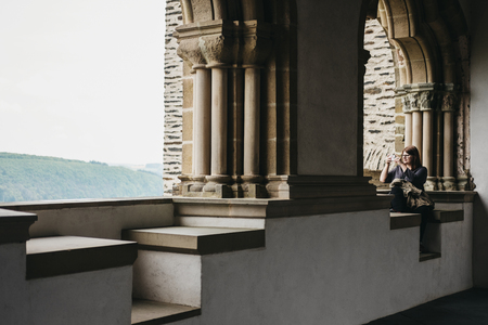 Vianden, Luxembourg - May 18, 2019: Woman taking pictures on mobile phone from Vianden Castle, Luxembourg, one of the largest and finest feudal residences of the Roman and Gothic eras in Europe.のeditorial素材