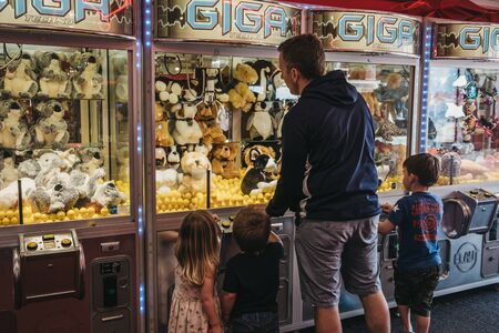Cromer, UK - April 20, 2019: Father and kids trying to win a soft toy from machine at the arcade by the seaside in Cromer, a seaside town in Norfolk and a popular family holiday destination in UK.のeditorial素材