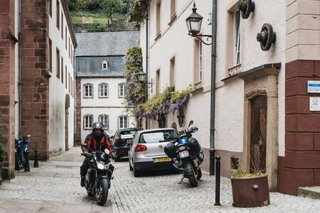 Vianden, Luxembourg - May 18, 2019: Motorcyclist on a narrow cobblestone street in Vianden, town in Luxembourgs Ardennes region known for the centuries-old hilltop Vianden Castle.のeditorial素材